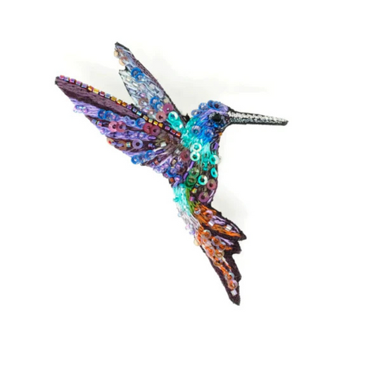 Hand embroidered and beaded hummingbird brooch. The little guy is a riot of color with a blue, purple, and silver on it's wings, a blue and purple head with a silver beak, a green body and orange and purple in it's tail. Brooch is covered in blue, purple, green, and clear iridescent micro sequins and beads.
It's very sparkly. 