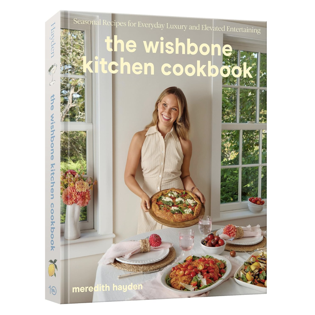 The Wishbone Kitchen Cookbook features the author holding a pizza in a bright kitchen setting