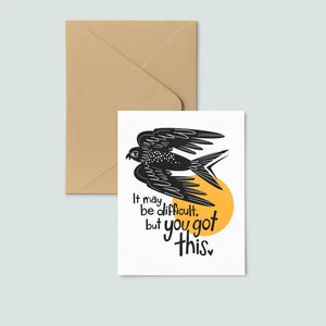 envelope underneath white card, print of black bird and text reading "it may be difficult, but you got this"