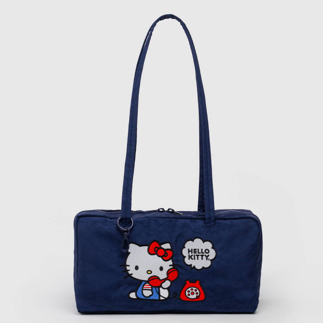 Navy blue bowler bag with embroidered Hello Kitty on a phone. Bag has long straps and a rectangle shape
