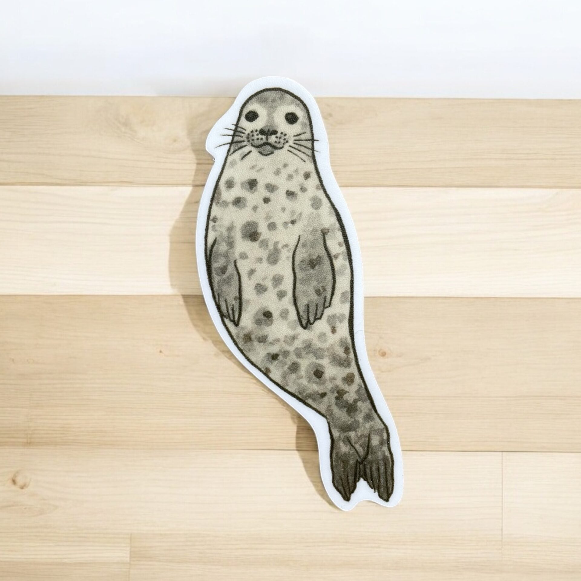 Adorable harbor seal sticker with a white boarder. Seal is freckled with a cutie-pie face and long whiskers.