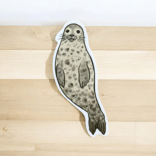 Adorable harbor seal sticker with a white boarder. Seal is freckled with a cutie-pie face and long whiskers.