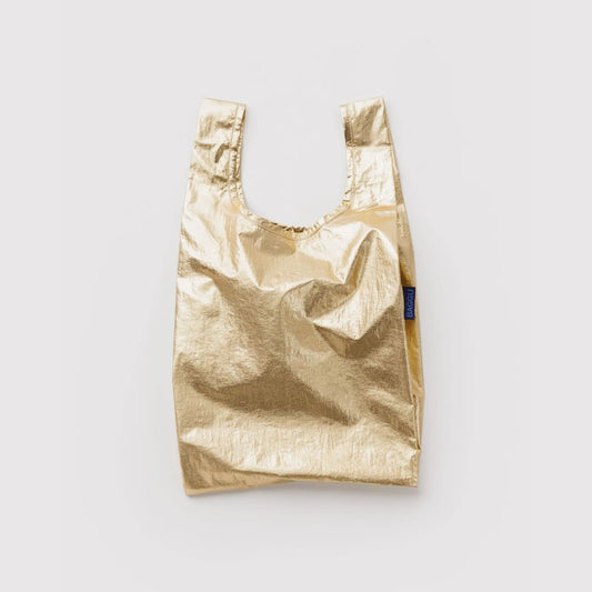 A metallic gold reusable shopping bag with integrated shoulder straps, shown against a plain light gray background. A small blue brand tag is visible on the right side.