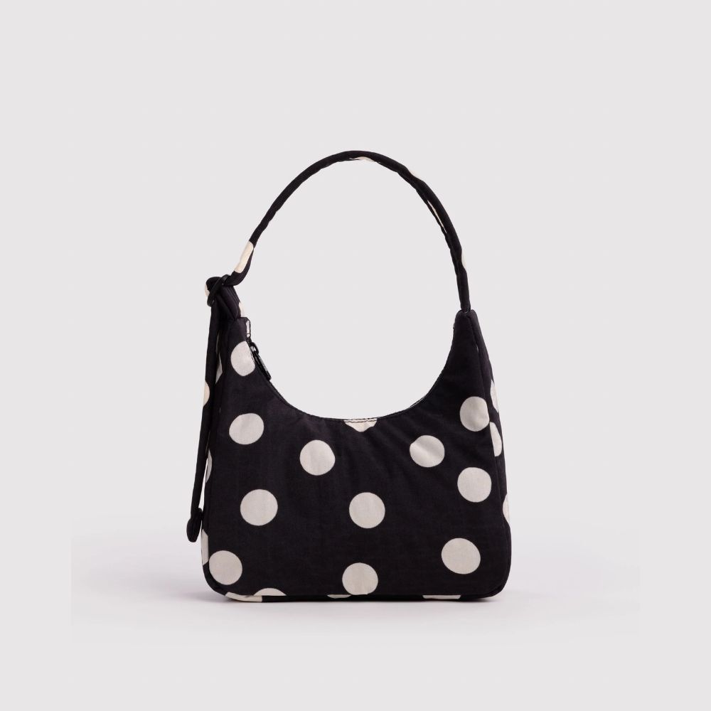 A black hobo shoulder bag with large white polka dots, featuring a single top handle and a side zipper, shown against a plain light gray background.