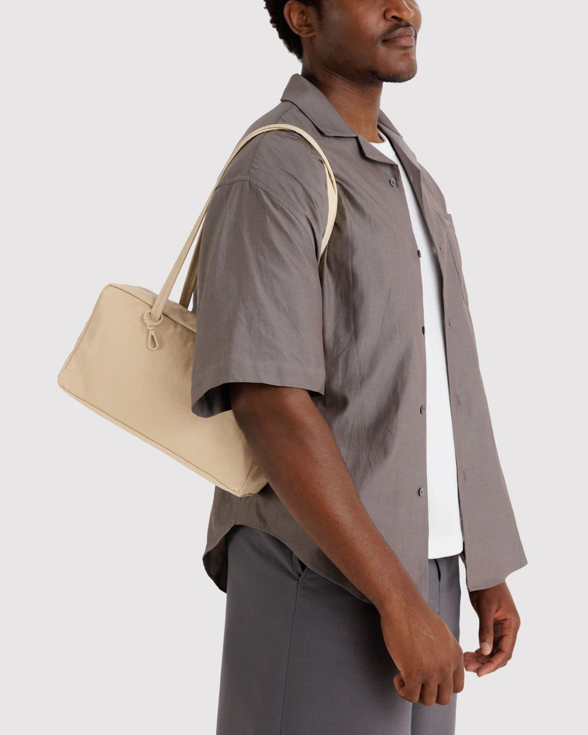 Man wearing a beige shirt with a beige handbag on a white background