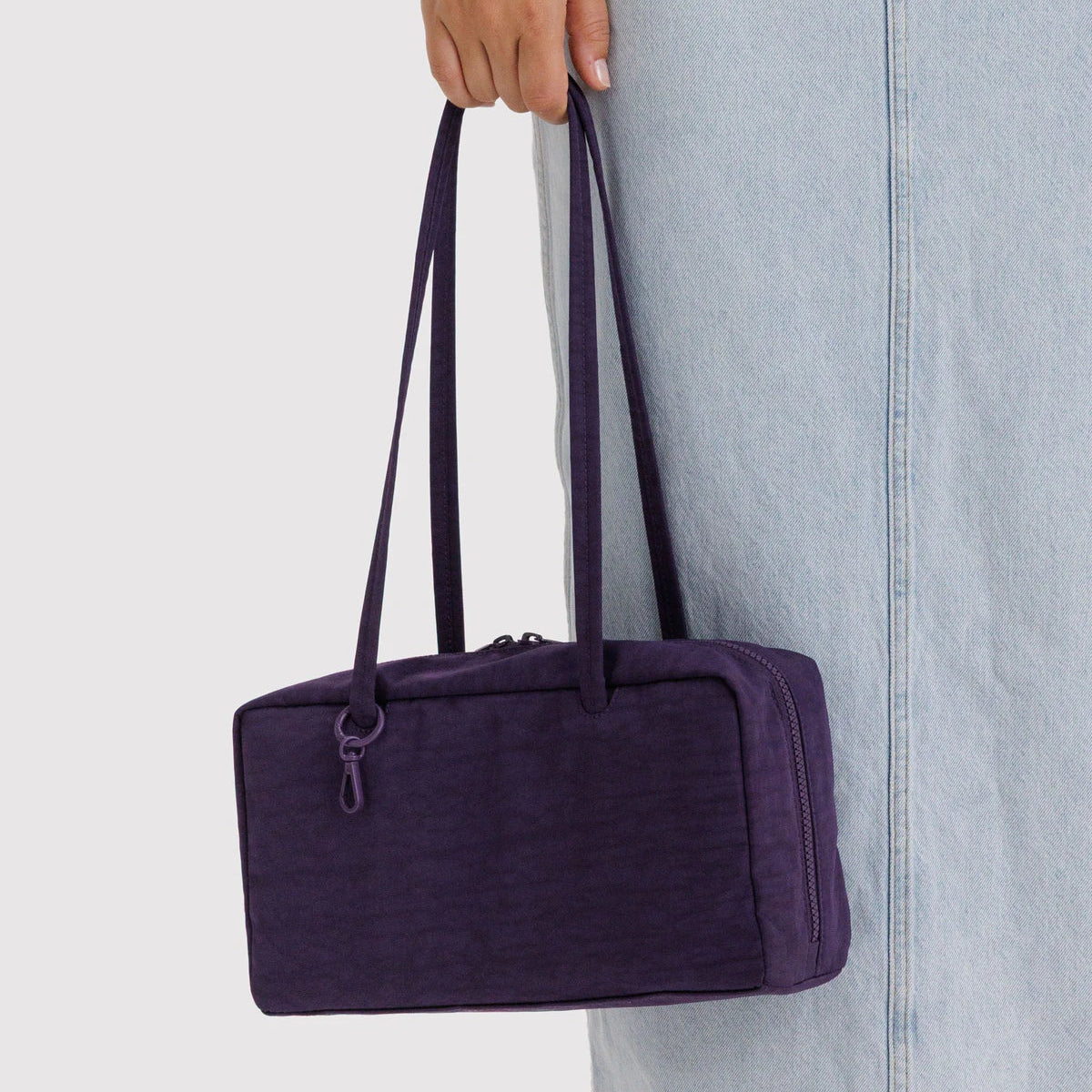Person holding a purple bag against a light gray background