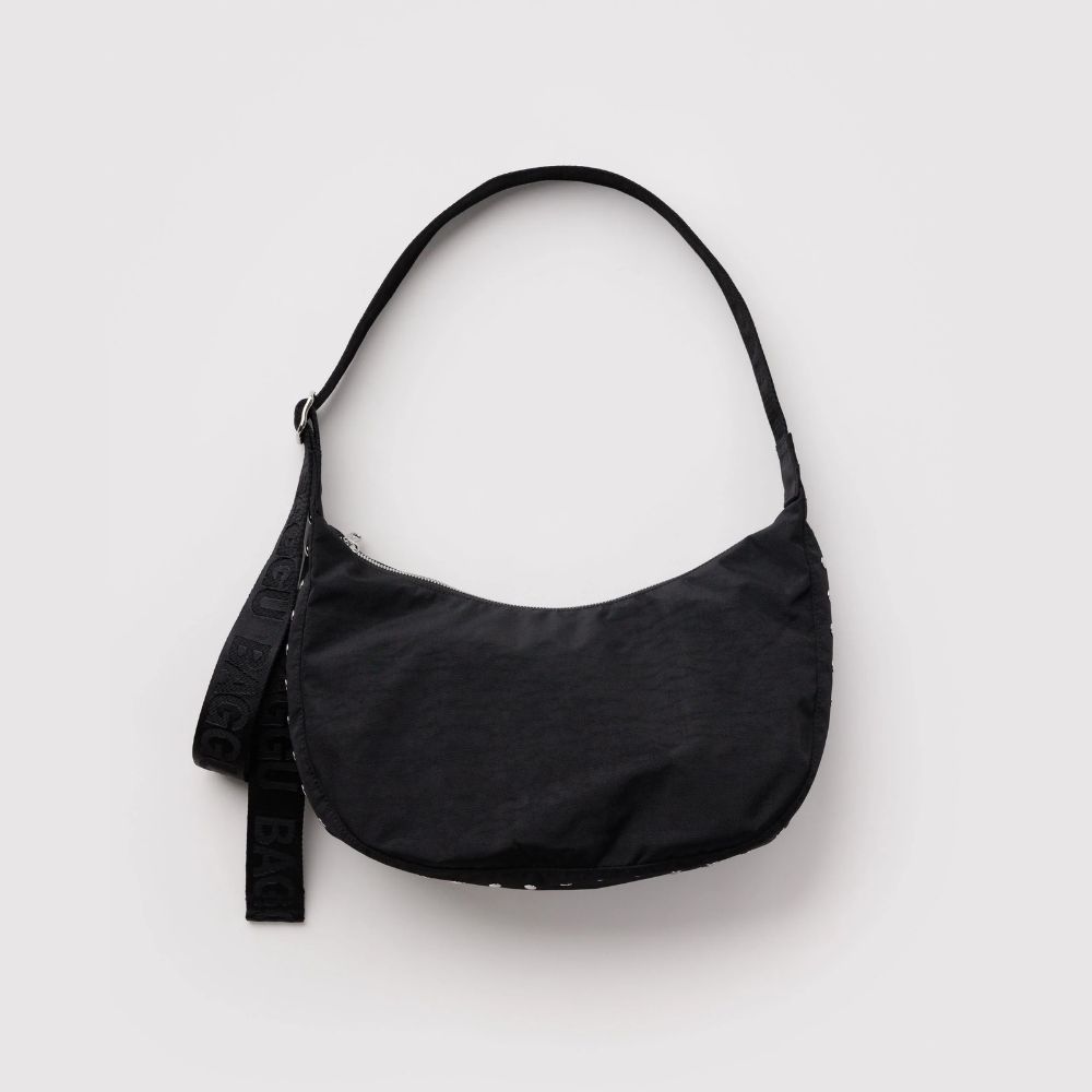 A black crescent-shaped shoulder bag with a matching black strap featuring white lettering, photographed against a light gray background.