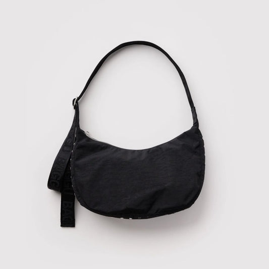 A black crescent-shaped shoulder bag with a matching black strap featuring white lettering, photographed against a light gray background.