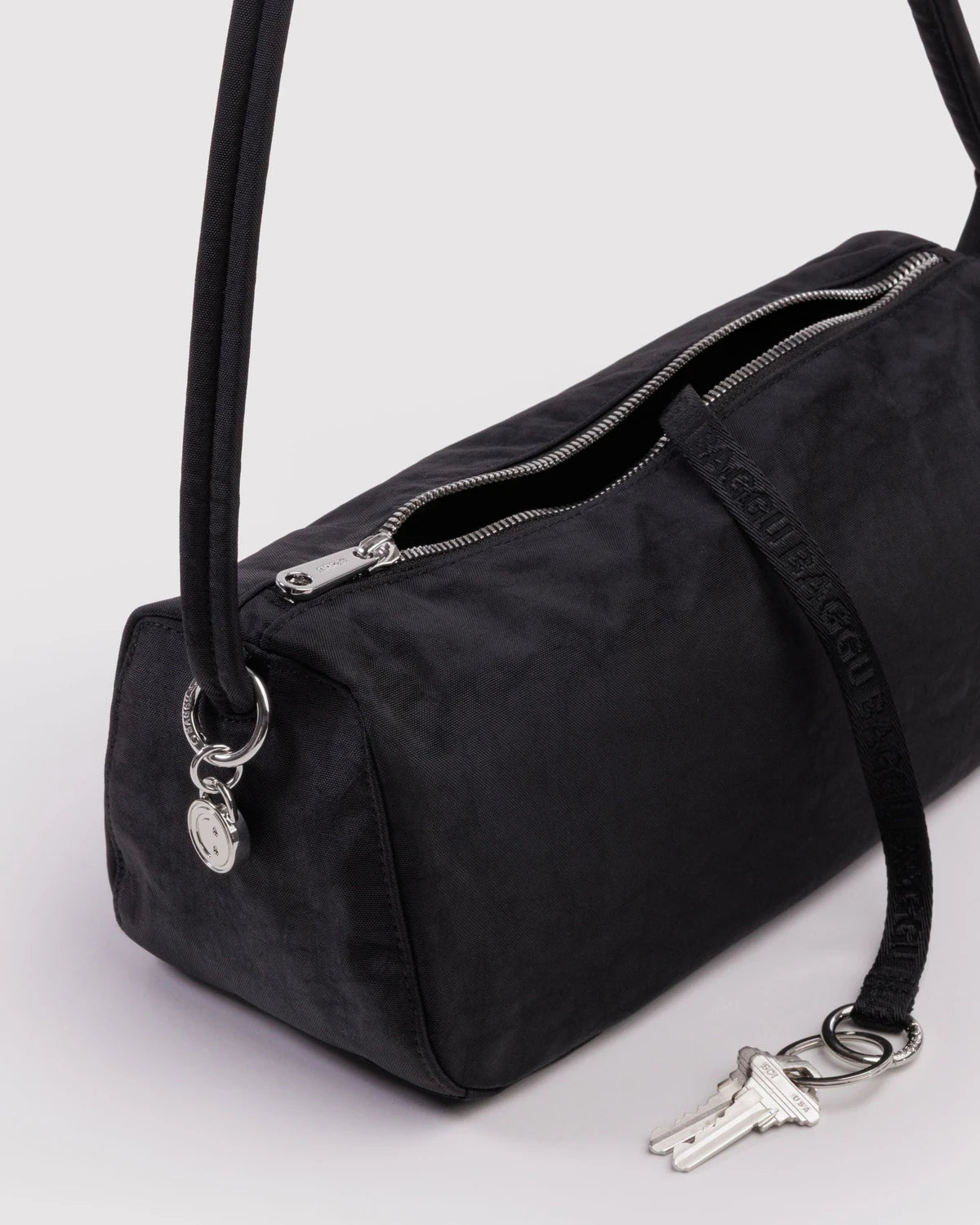 Black handbag with a strap and keychain on a light gray background