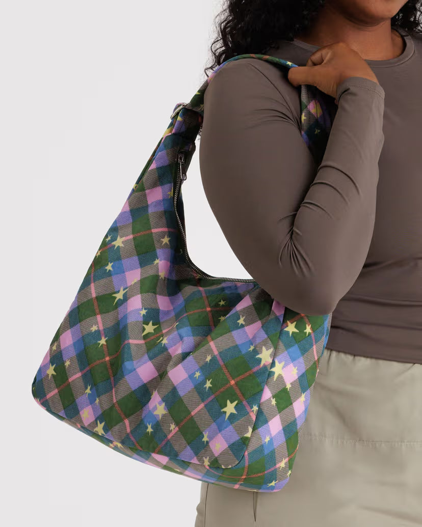 Person holding a colorful plaid bag against a white background