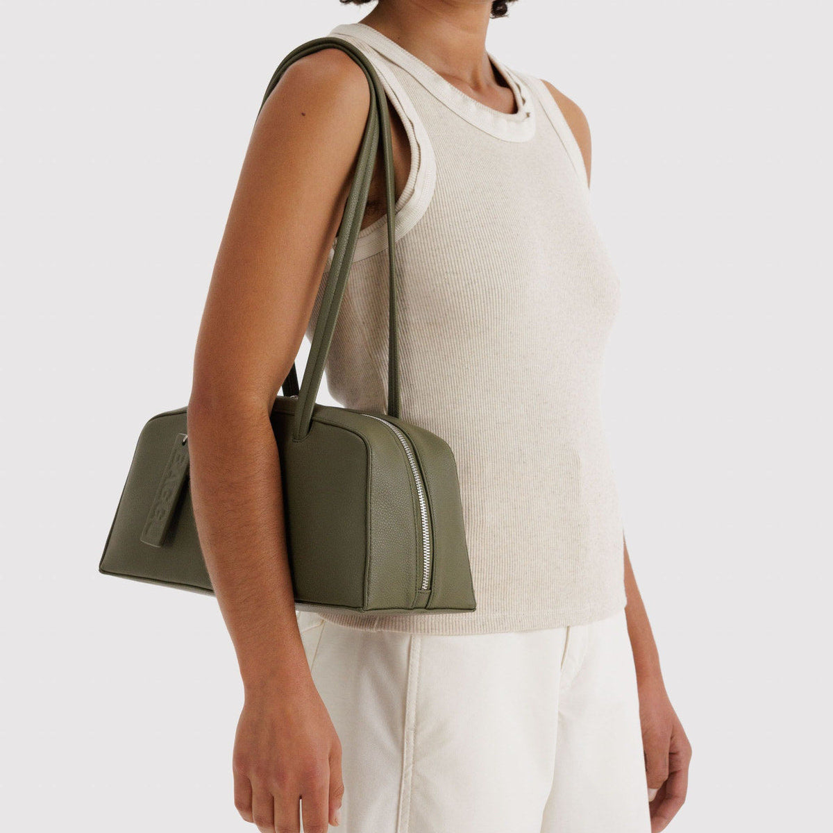 Woman holding a green handbag against a white background