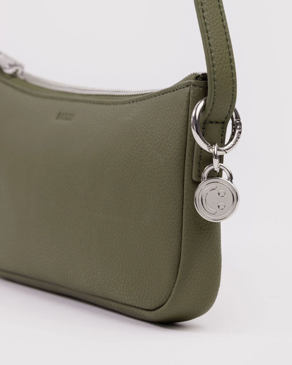 Green handbag with a silver smily face charm on a white background