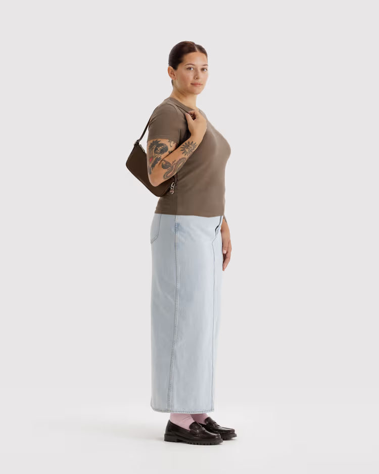 Woman wearing a brown top and light blue jeans, holding a brown bag on a white background