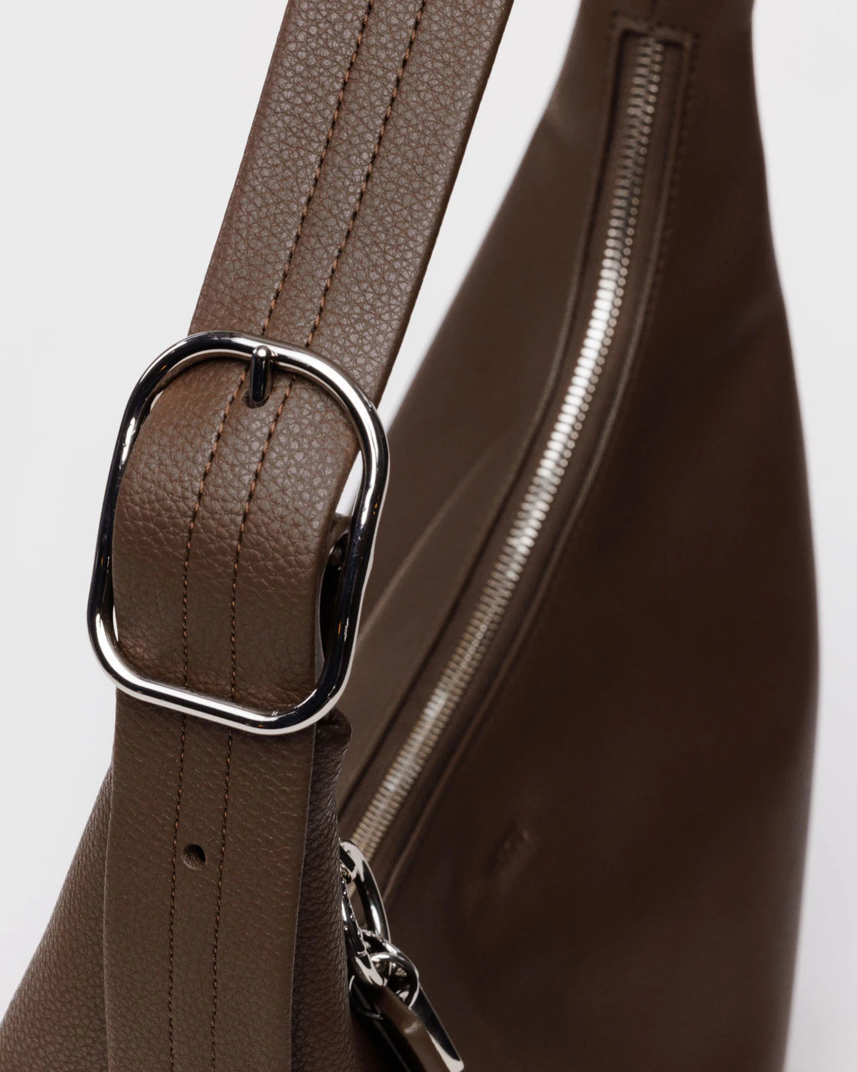 Close-up of a brown leather bag with a silver buckle on a light gray background