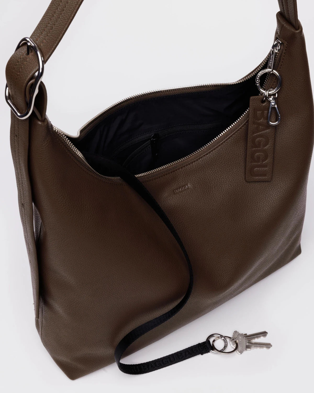 Brown leather handbag with a strap and keys on a white background