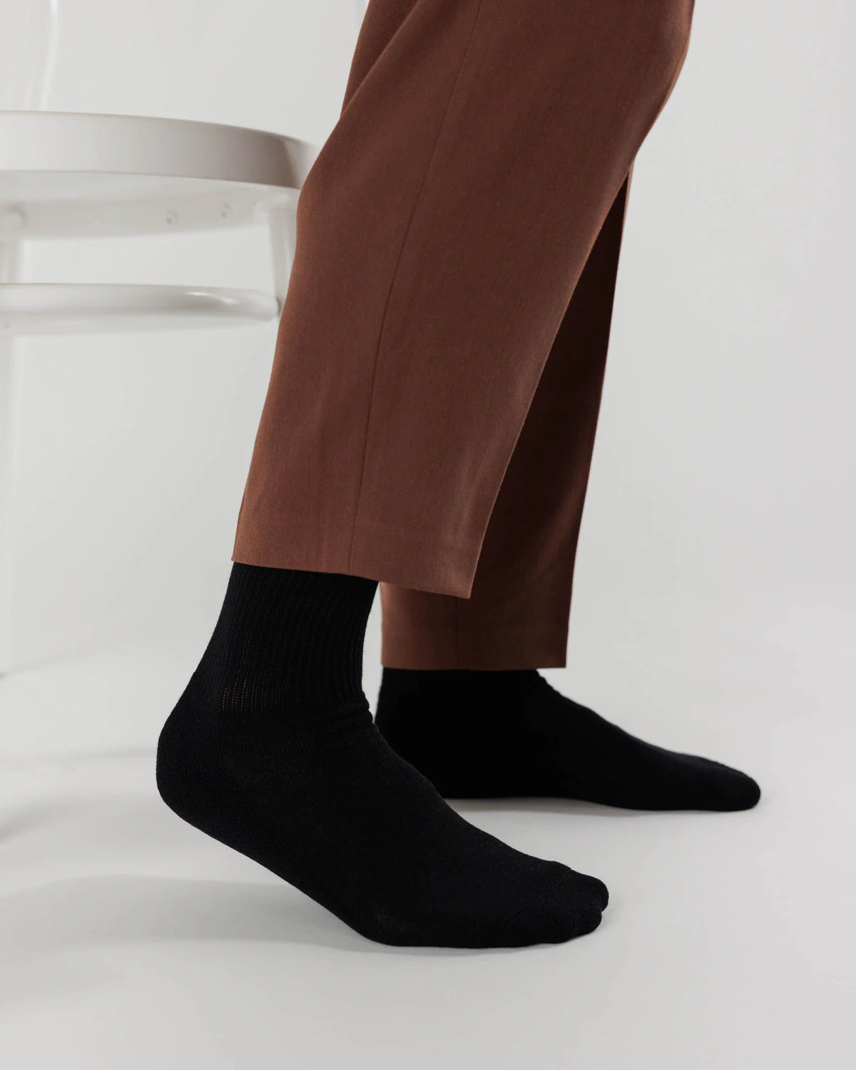 Person wearing black socks and brown pants on a white background