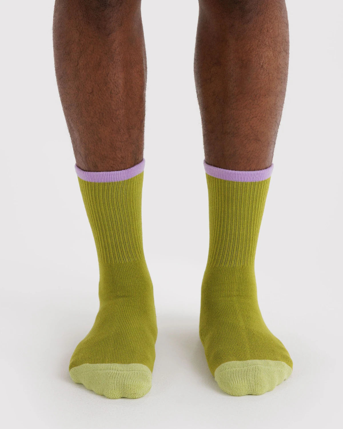Green socks with purple accents worn by a person on a white background