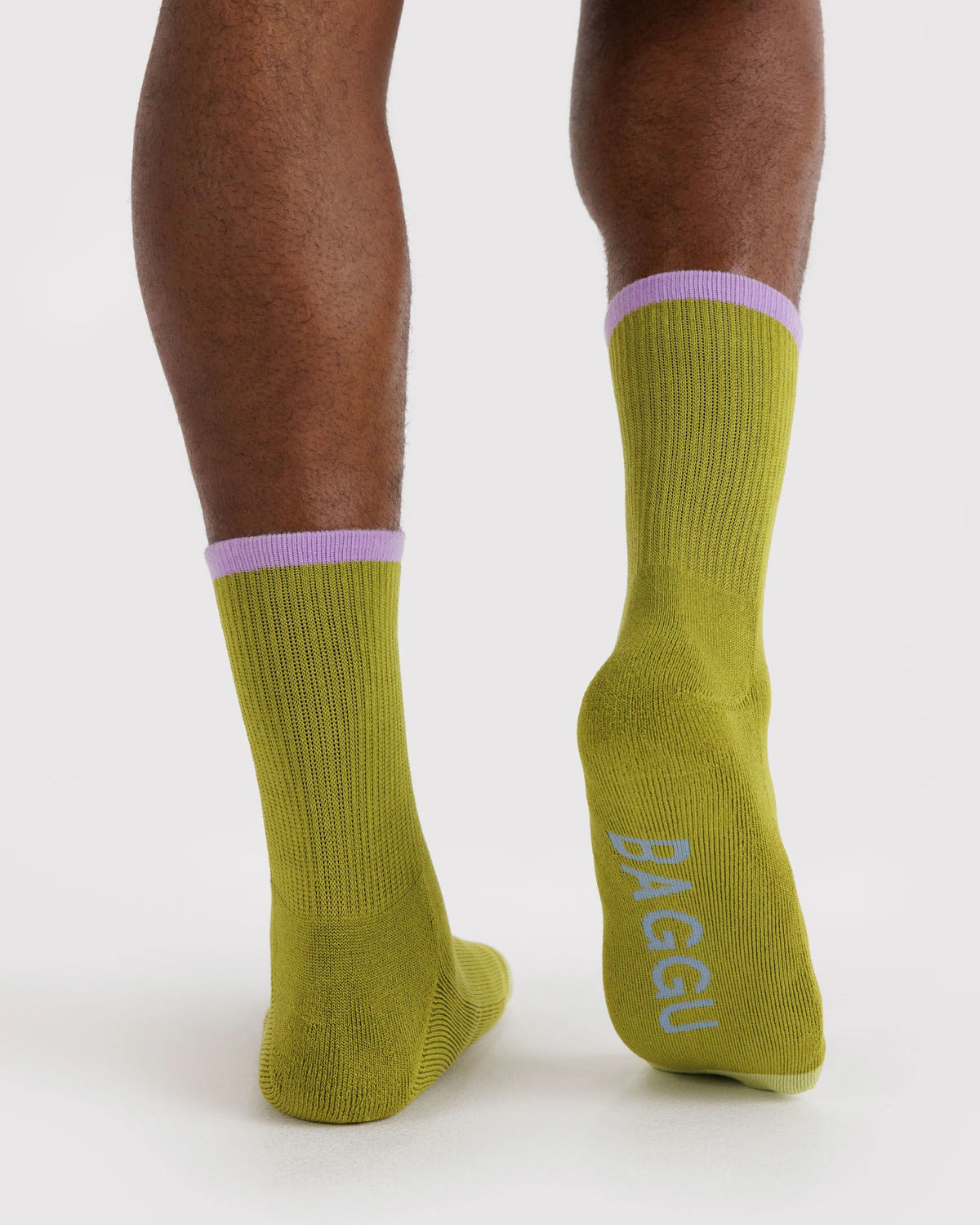 Green socks with purple accents worn by a person on a white background