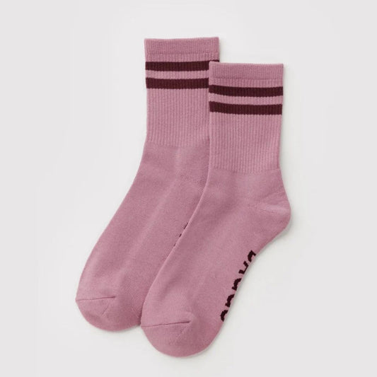 A pair of dusty pink crew socks with dark brown stripes near the cuff and dark brown text on the sole, displayed on a light gray background.