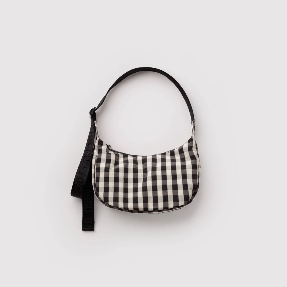 A small crescent-shaped shoulder bag with a black and off-white gingham check pattern, featuring a black strap, shown against a plain light gray background.