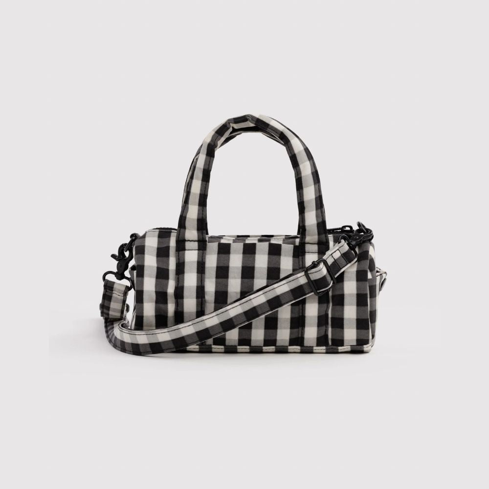 A black and white buffalo check patterned handbag with dual top handles and an adjustable shoulder strap, shown against a light gray background.