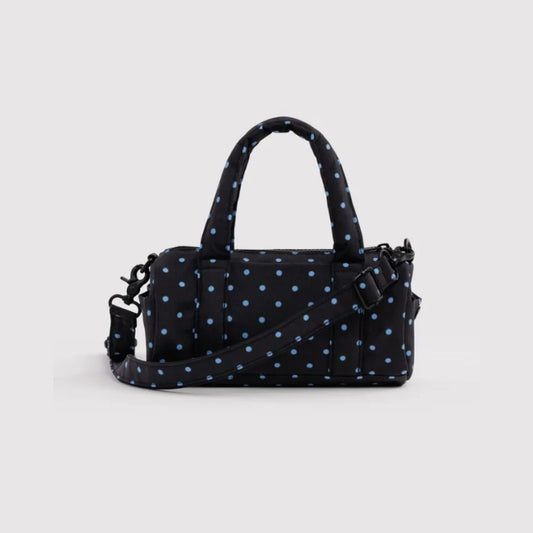 A black nylon handbag with a light blue polka dot pattern, featuring dual top handles, a detachable shoulder strap, and a zip-around closure, shown against a light gray background.