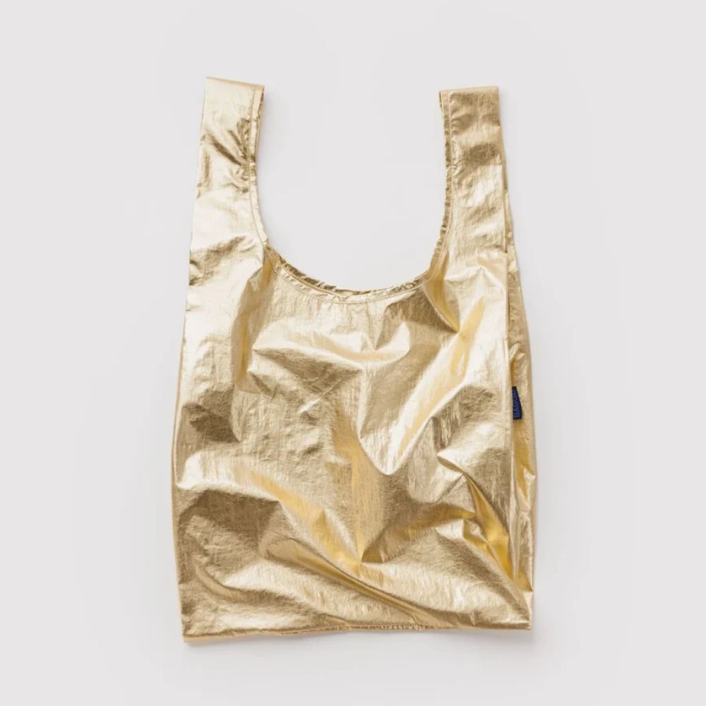 A metallic gold reusable shopping bag with a wide scoop-style opening and integrated shoulder straps, shown flat against a light gray background.