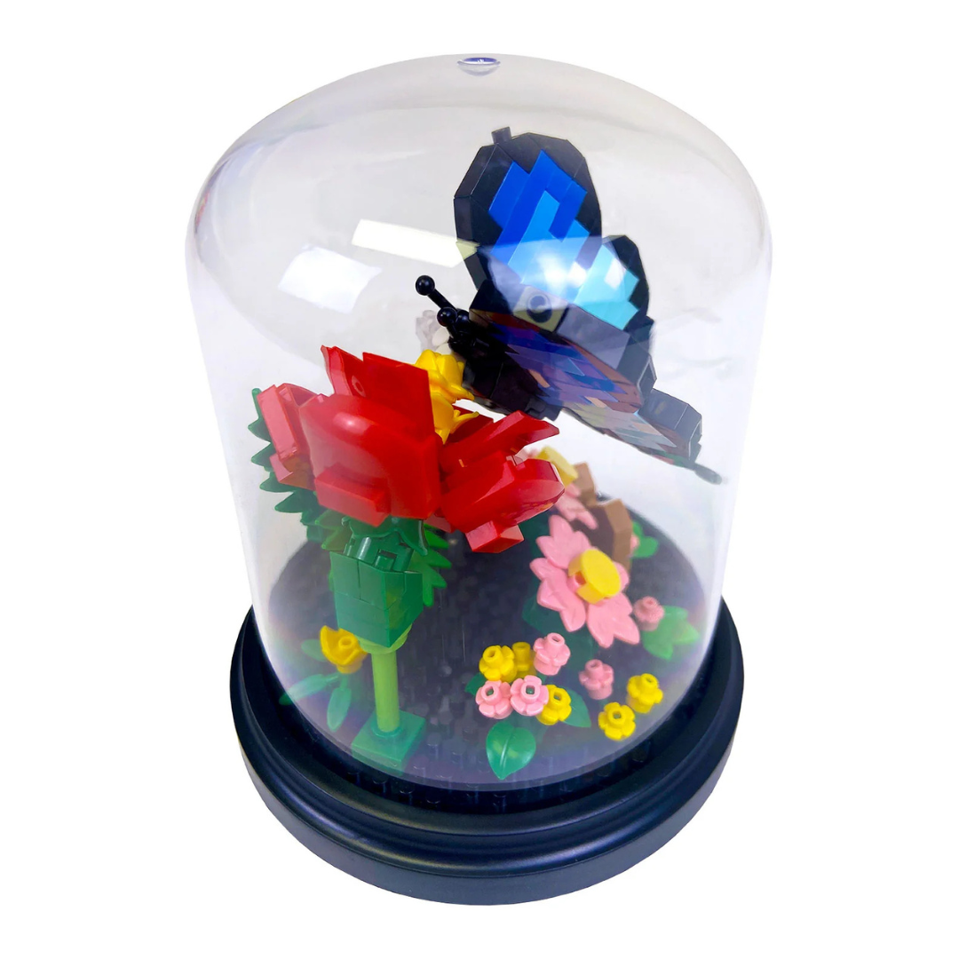 Toy blocks of a blue butterfly with flowers inside a transparent dome on a white background