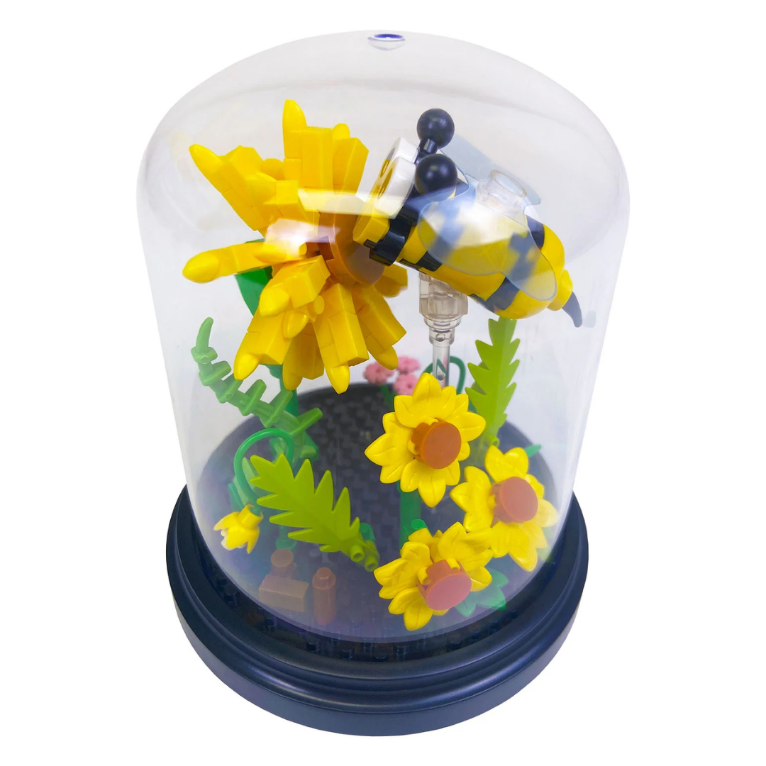 Toy block bee and flowers inside a clear dome on a white background