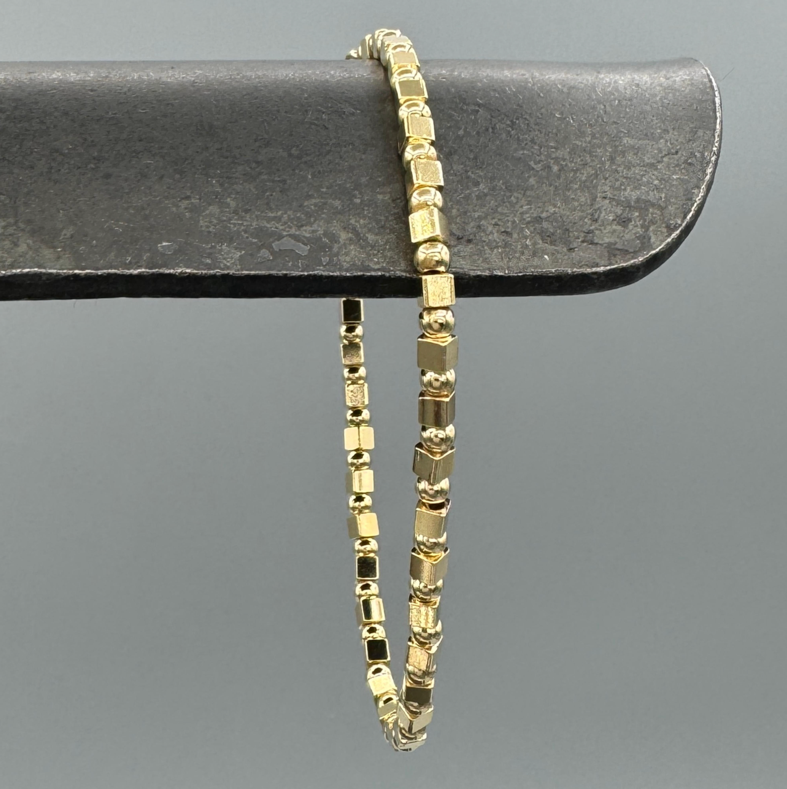 Gold bracelet on a dark gray surface