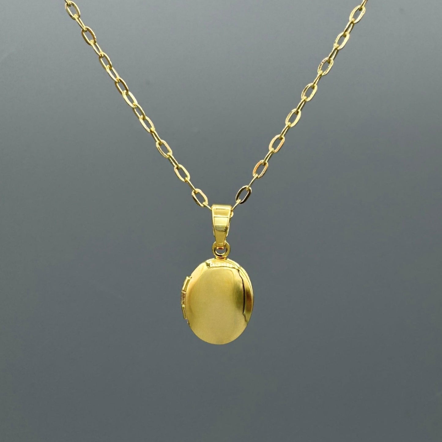 Gold locket necklace on a dark gray background