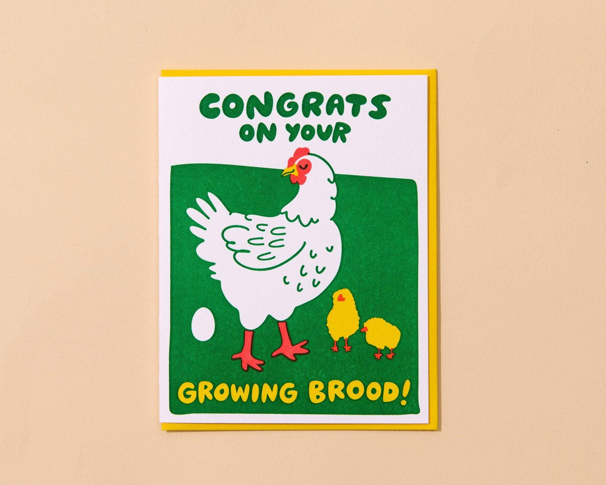 Greeting card with a chicken and chicks illustration and text on a beige background That says "Congrats On Your Growing Brood!"