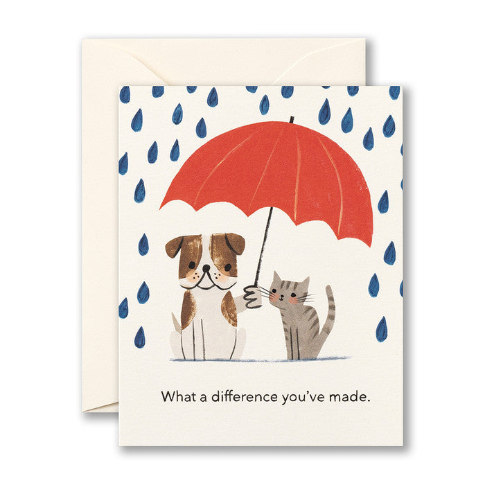 Card with an English bulldog holding a red umbrella over themself and a gray tabby cat while big blue raindrops fall.
Card reads "What a difference you've made"