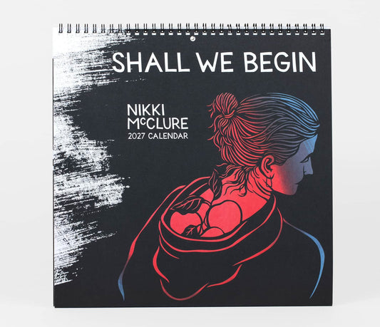 A spiral-bound 2027 calendar titled 'SHALL WE BEGIN' by Nikki McClure, featuring a black cover with a stylized illustration of a woman carrying a baby in red, blue, and pink tones.