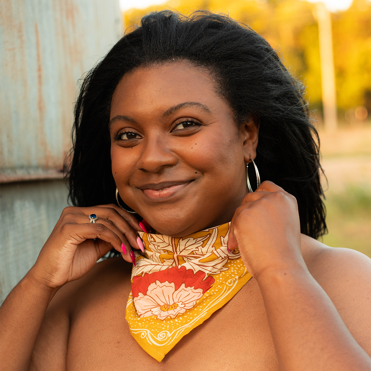 Woman wearing a colorful bandana with a blurred outdoor background