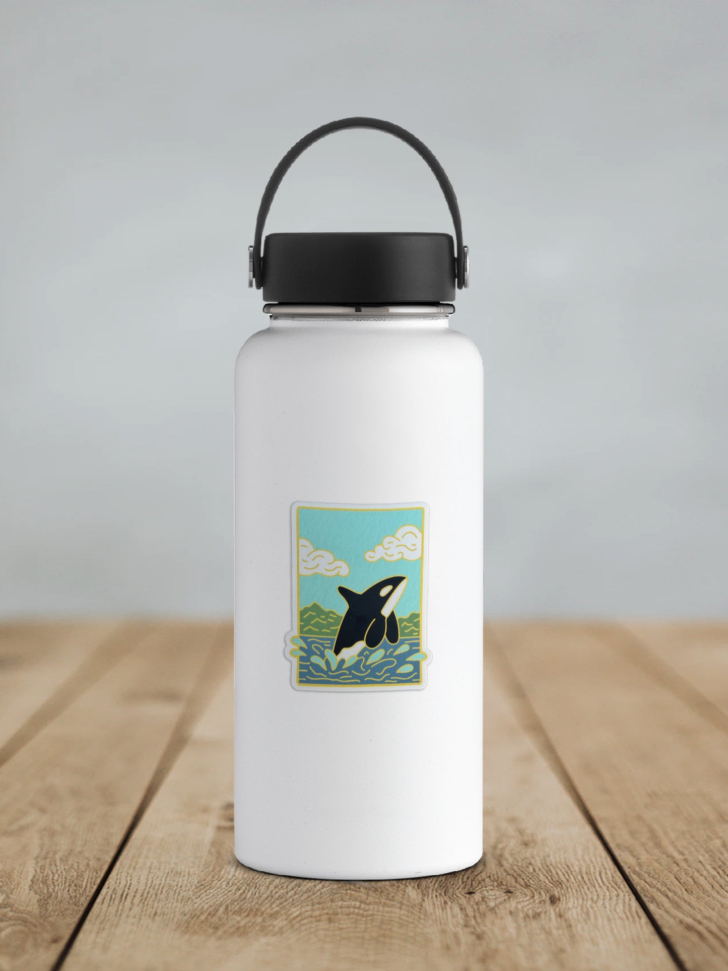 Sticker design featuring an orca jumping out of the water with mountains behind on a white water bottle.
