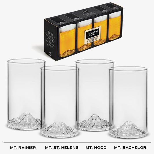 Four clear pint glasses with mountain-shaped bases, shown with their black retail box. Featuring Mt. Rainier, Mt. St. Helens, Mt. Hood, Mt. Bachelor.
