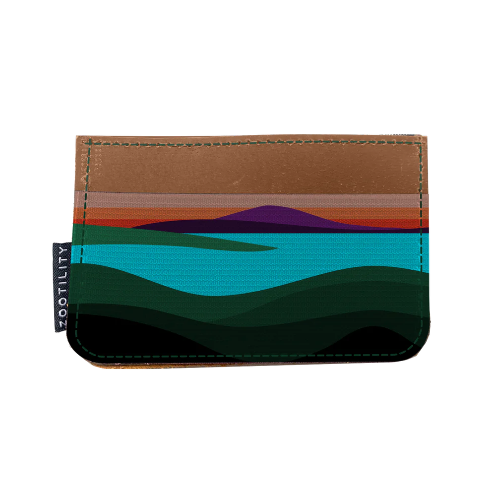 Leather card holder wallet has a pocket with an abstract landscape design.