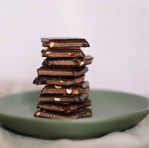 Pieces of chocolate bar stacked in a tower on a green plate.