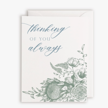 White card and envelope. Blue text saying "Thinking of You" with teal floral design below.