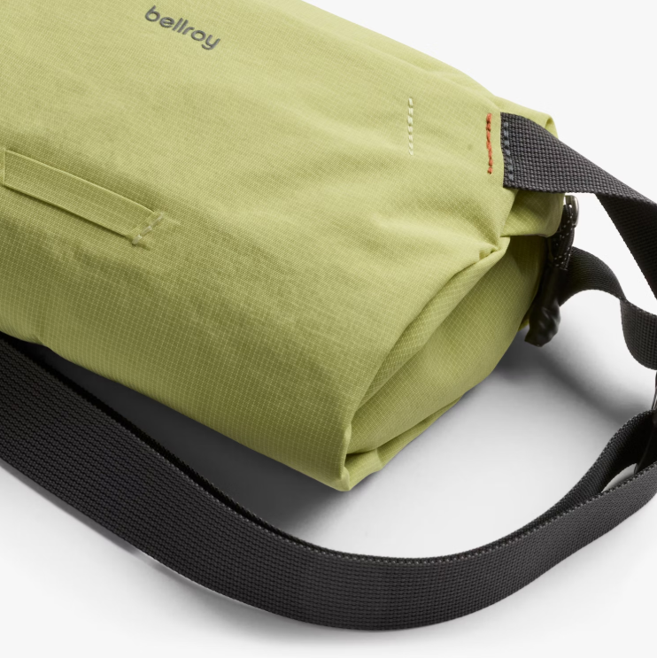 Close up of the side of a green sling bag with black strap.