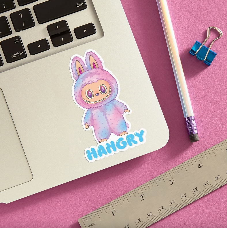 Pink, purple, and blue Labubu sticker with the word Hangry in blue under it on laptop with pink background.