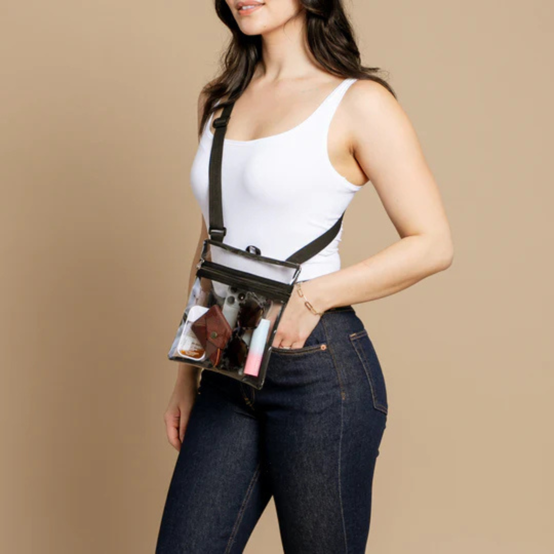 Model in jeans and a tank top wearing the crossbody bag across her body. Bag is full of essentials such as a phone, glasses, and wallet.
