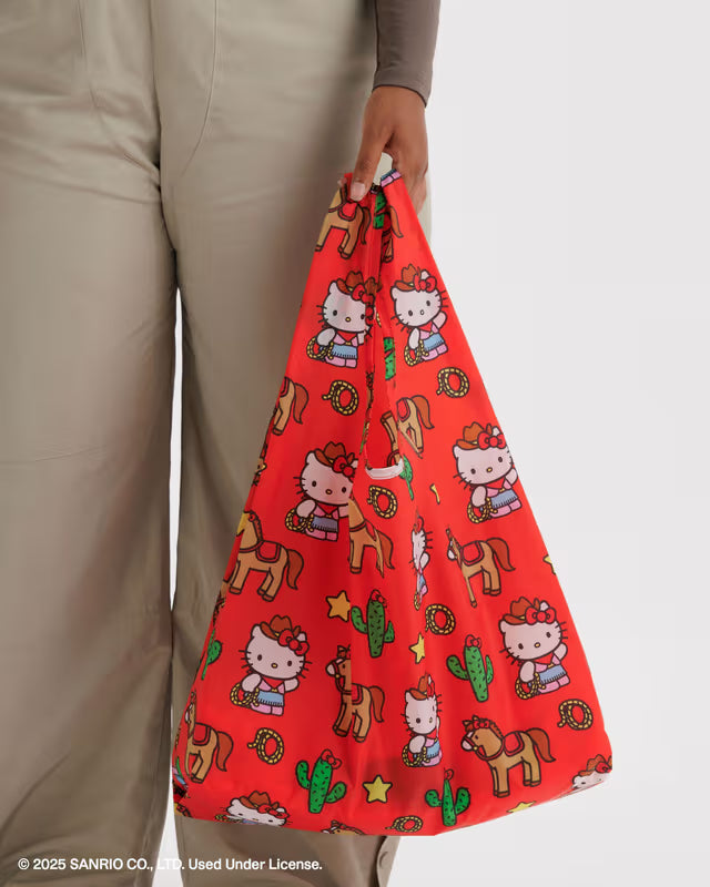 Person holding a red reusable bag with Hello Kitty and horse design.