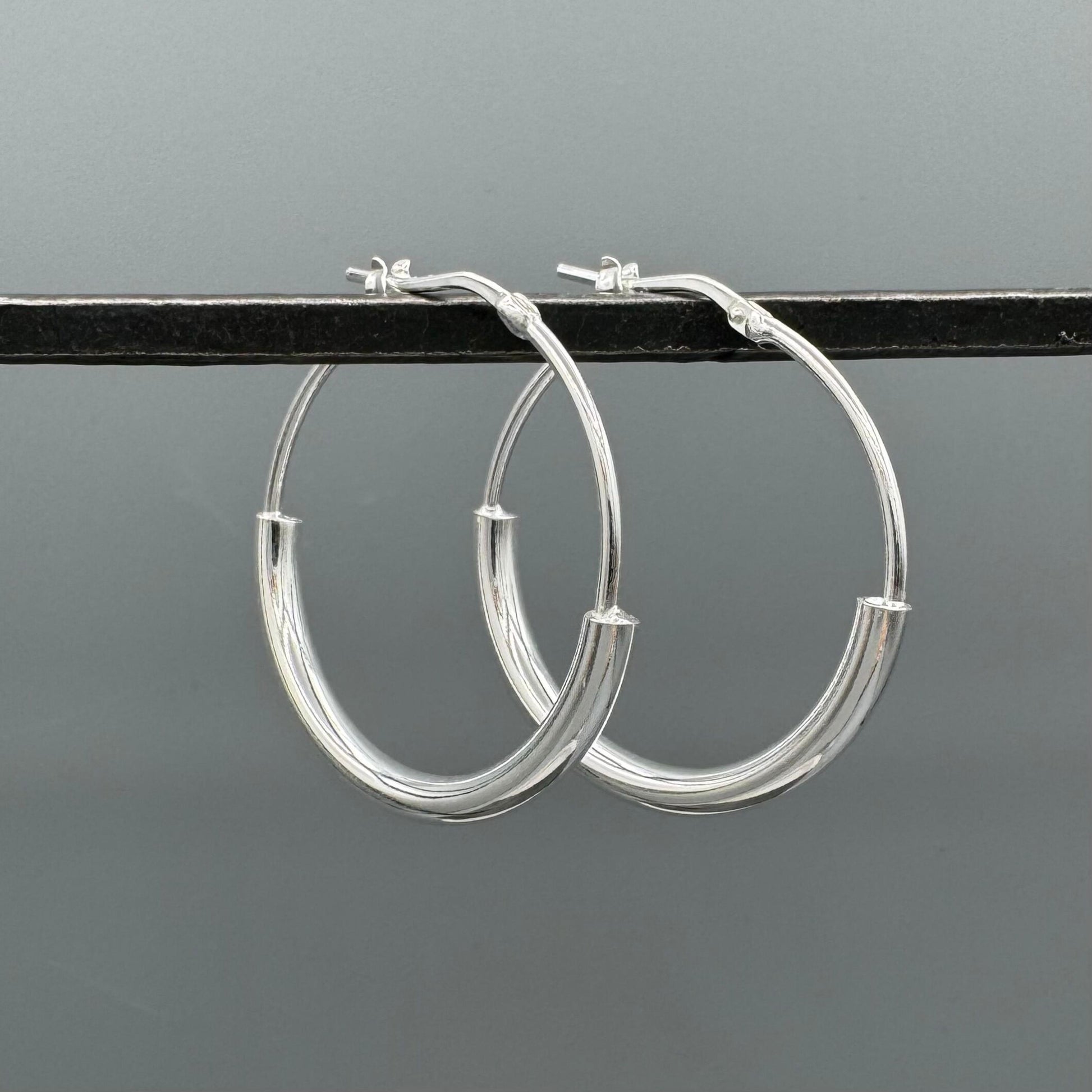 Silver hoop earrings on a gray background