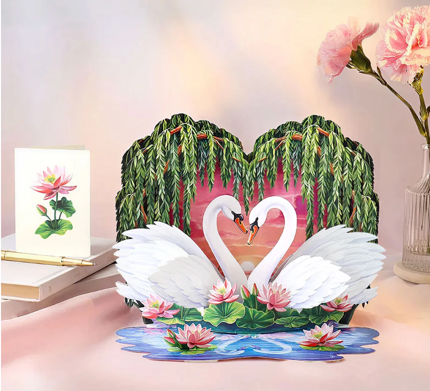 3D pop-up card with swans and willow branches on a decorative stand.