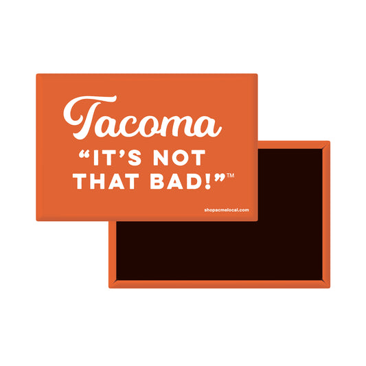 An orange rectangular magnet with white text reading 'Tacoma IT'S NOT THAT BAD!' 