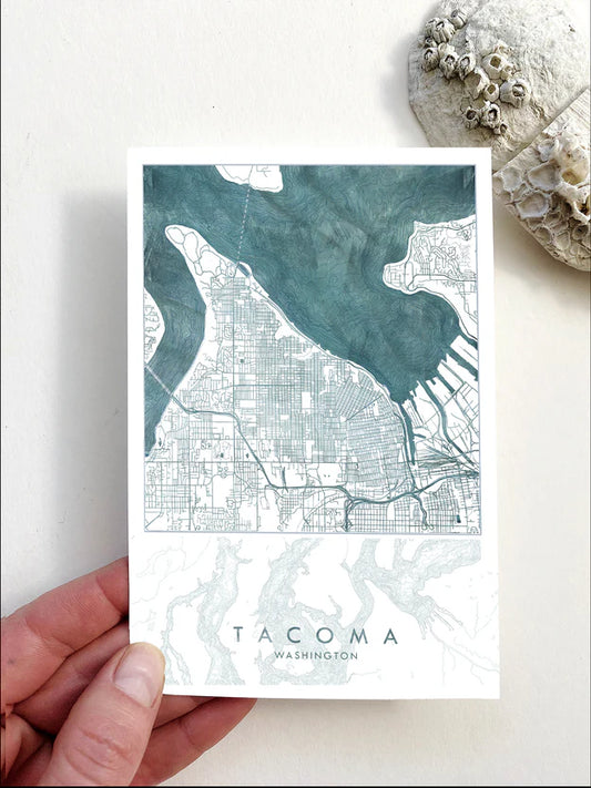 Postcard of a map of Tacoma held by a hand on a light background