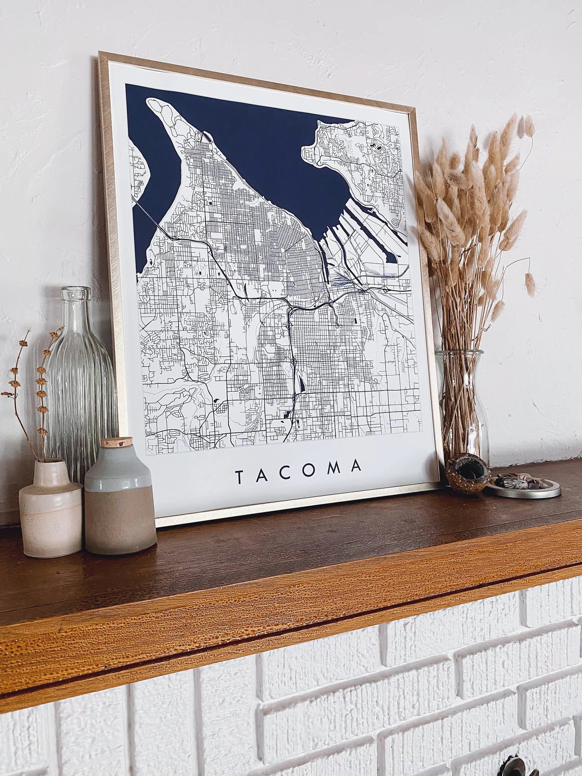Framed map of Tacoma on a wooden shelf with decorative items.