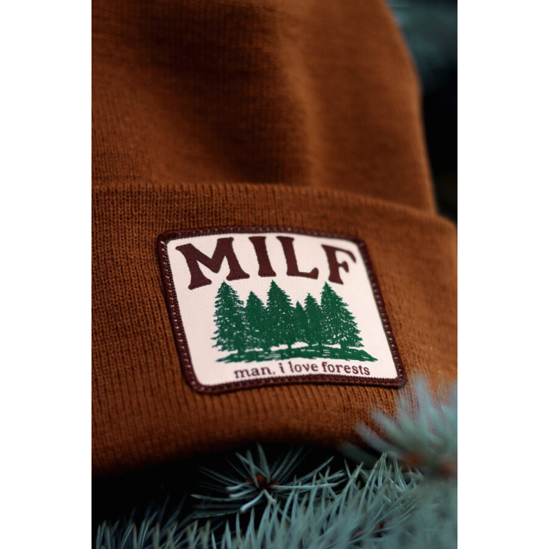 Rusty brown beanie with a white rectangular patch featuring green trees and the words "MILF" and "man I love forests".